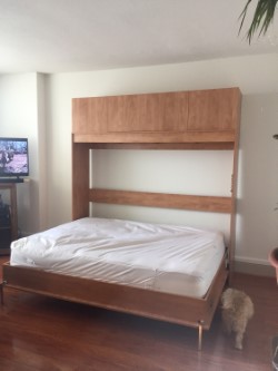Opened Queen size horizontal Murphy bed with a cabinet above in Light Cherry finish