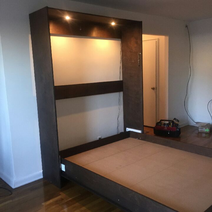 Vertical Queen sized Murphy Bed in a Stained Wood Vaneer finish showing custom white custom lighting